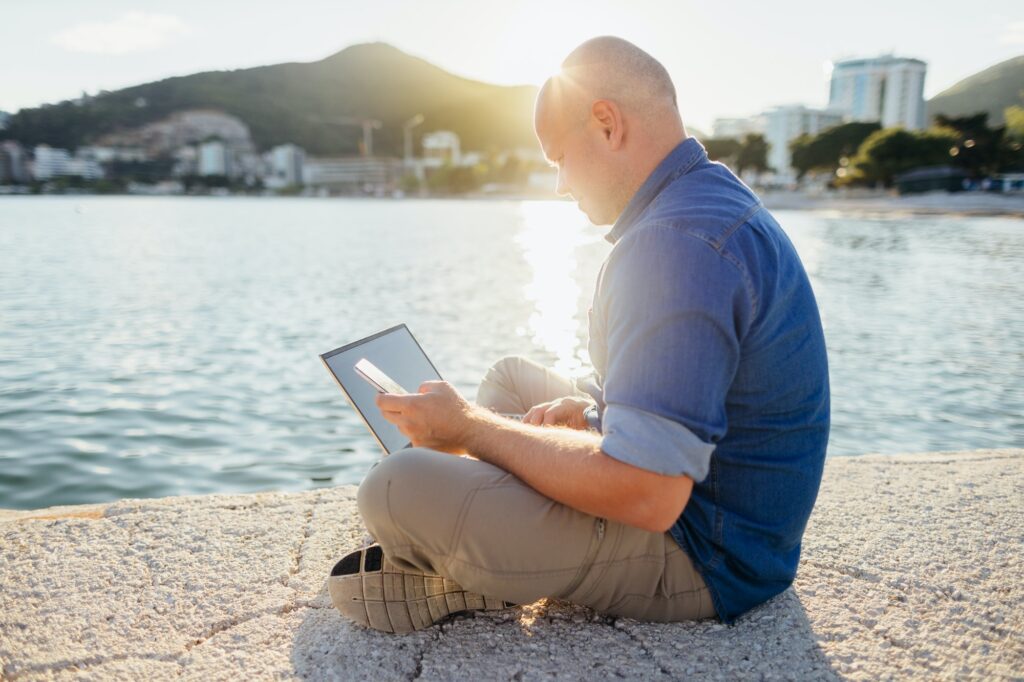 man using laptop at seaside